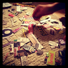 Sepia-toned photo of words cut out of magazines lying on the floor as though ready to be made into a ransom note.