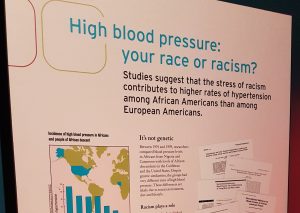Photo of plaque titled "High blood pressure: your race or racism?" Subtitle: "Studies suggest that the stress of racism contributes to higher rates of hypertension among African Americans than among European Americans. Map graphic shows high blood pressure of U.S. blacks and low blood pressure of related Africans.