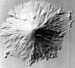 Image shows Mount St. Helens from above, in grayscale, without trees. The stream gullies and lava flows trailing down its flanks are clearly visible. It's an almost symmetrical cone.