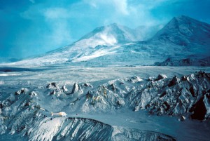 Image shows the remains of Mount St. Helens from the ground, looking across lahar flows and blast deposits to the steaming crater that has hollowed the mountain. There's not a single plant or tree left.