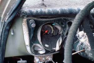 Image shows a car's instrument panel, which has been half-melted and is covered in dark-gray ash.