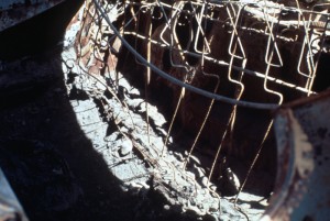 Image shows the ash-coated remains of a vehicle seat. All that's left is the wire frame.