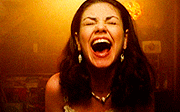 Image shows Jackie from That 70s Show laughing: she's a woman with long dark hair against a golden-brown background.