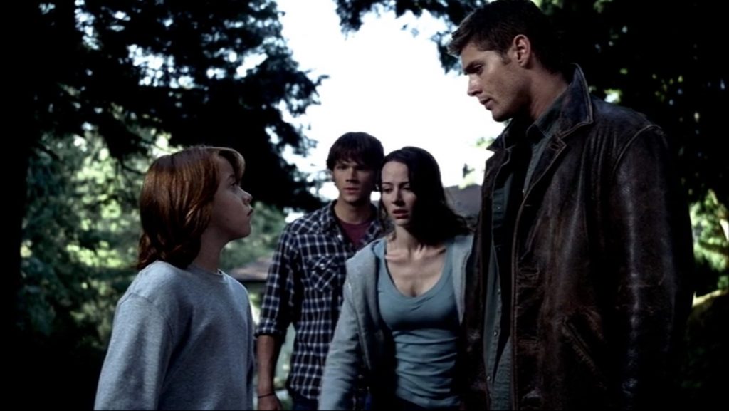 Screenshot is an outdoor scene. Lucas and Dean stand in the foreground, staring intently at each other, while Andrea and Sam look on.