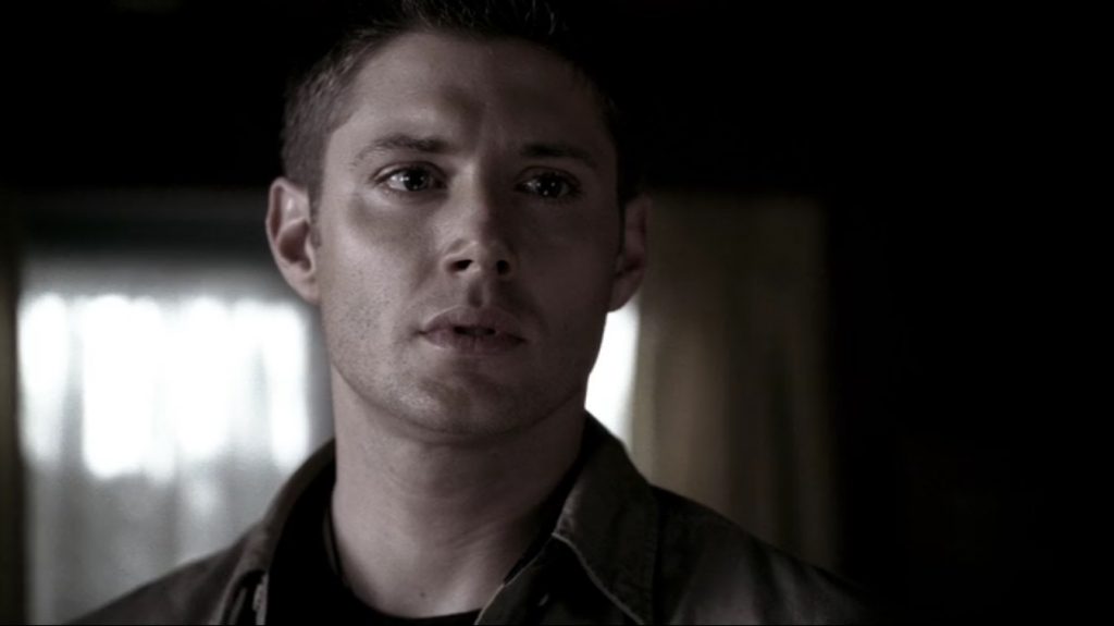 Image shows Dean looking mournfully at something off-camera, his eyes glistening with just a hint of tears.