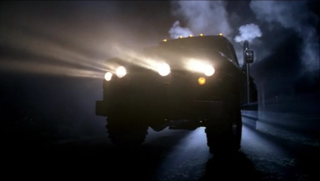 Screen capture shows a silhouette of the racist truck, all four headlights blazing, steam coming from its back.