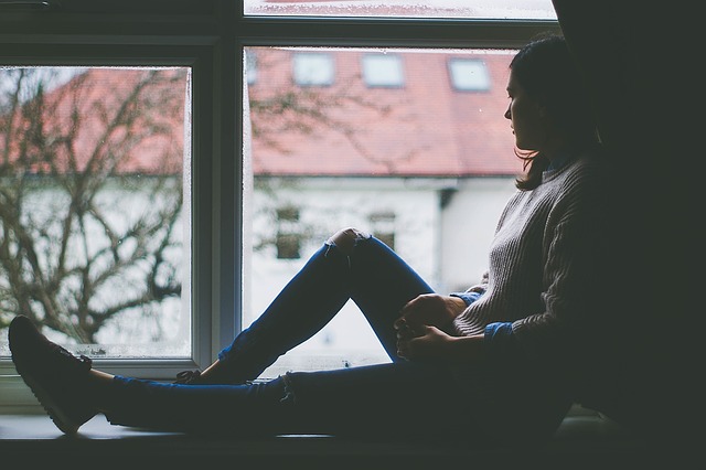depressed woman sitting in window seat