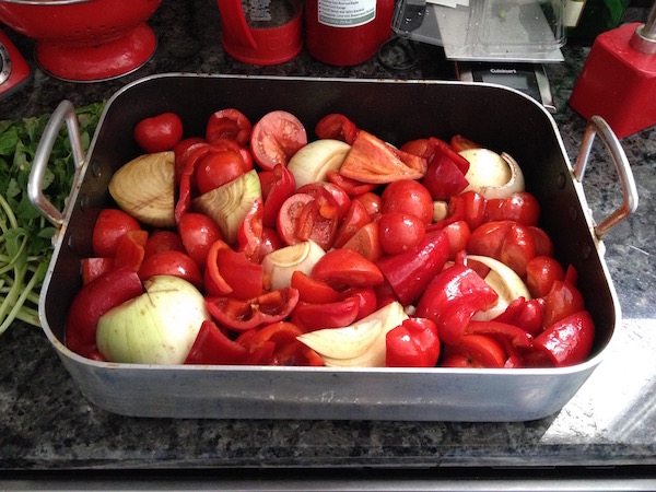 Ingredients for roasted tomato sauce in pan cut up tomatoes red bell peppers garlic onions