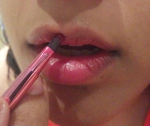 Heina applying lip color to her lips with a brush
