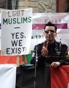 a person in sunglasses flashing the peace sign. to their right is a sing that says "LGBT MUSLIMS - YES, WE EXIST"