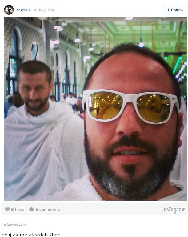 a man in white sunglasses with colored frames and a fairly full (but not long) salt & pepper beard standing in front of another Muslim Hajj pilgrim in draped white garments
