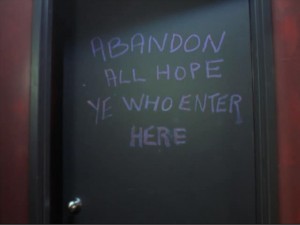 A chalkboard with "ABANDON ALL HOPE YE WHO ENTER HERE" written on it