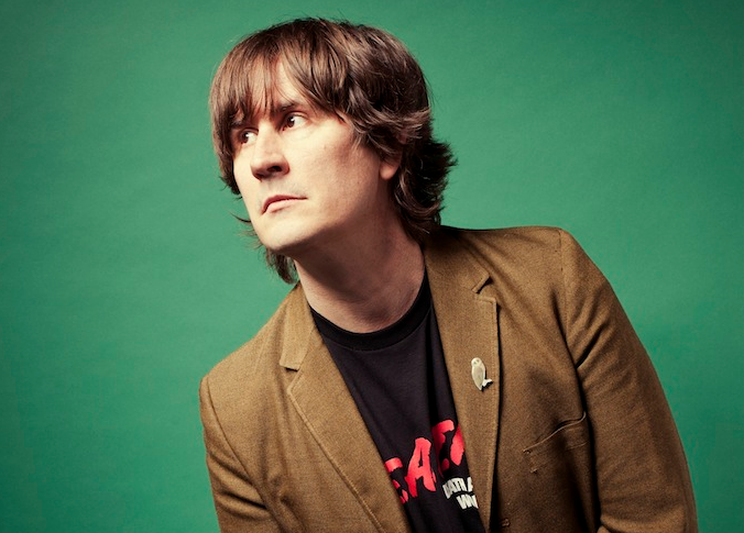 Shot of John Darnielle on a green background.